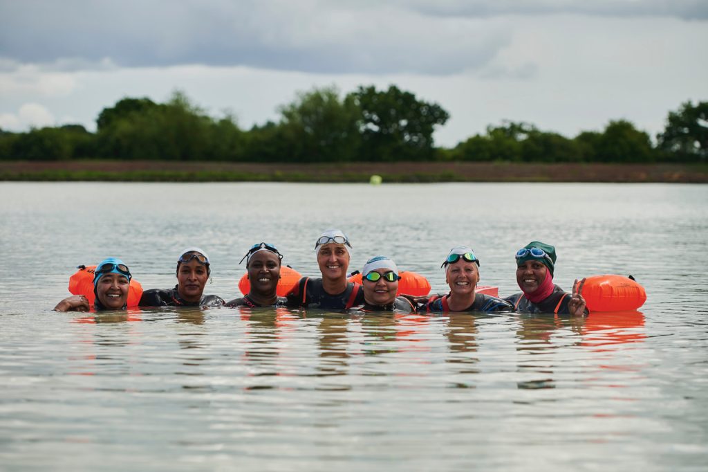 image-wave-left a group of women swimming in the lake pose for a picture together.